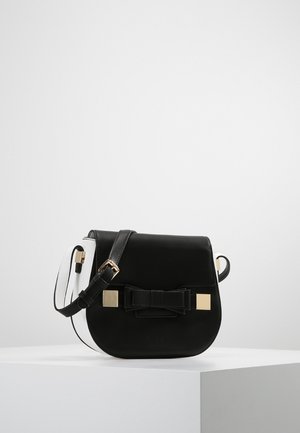 Bolso bandolera de cuero negro con forma redondeada, detalles en herrajes dorados y un lazo prominente en la parte frontal. Correa ajustable.