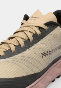 Beige sportieve schoen met een gestructureerde synthetische bovenkant, grijze accenten, roze tussenzool en een donkere rubberen buitenzool. De veters zijn tan met stikdetails.