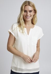 Weißes Blusenshirt mit kurzen Ärmeln, einem tiefen Ausschnitt und einer Tasche. Glatte Textur mit einem transparenten Saumdetail am unteren Ende.