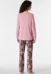 Top a maniche lunghe rosa con scollatura rotonda abbinato a pantaloni marroni con un motivo floreale in rosa chiaro e accenti in crema.
