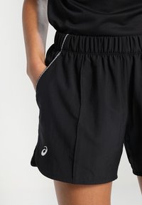 Shorts de sport noirs avec une taille élastique, des poches latérales et une bordure réfléchissante. Avec un petit logo sur l'ourlet inférieur.