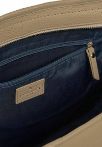 Intérieur d'un sac en cuir beige montrant une doublure en tissu bleu marine, une poche zippée avec une tirette en cuir, et une étiquette de marque en cuir cousue portant la mention "LAZAROTTI."
