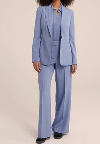 Jasnoniebieski, dopasowany garnitur składający się z marynarki i szerokich spodni, charakteryzujący się gładką fakturą i pojedynczym guzikiem zapinającym marynarkę.