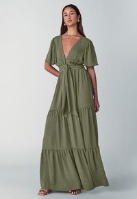 Maxikleid in olivgrün mit tiefem V-Ausschnitt, kurzen Puffärmeln, gestuftem Design und gebundenem Taillengürtel. Glatte Textur und fließender Stoff.