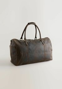 Bruine leren reistas met twee ronde handvatten, ritssluiting, zijvak, gladde textuur, rechthoekige vorm en zichtbare stikdetails.