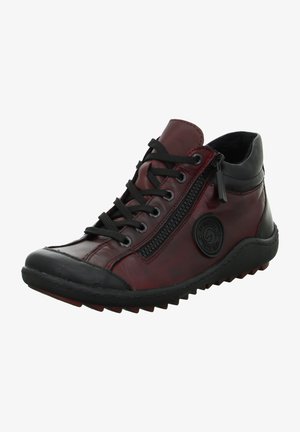 Botte de cheville en cuir rouge avec accents noirs, fermeture à lacets et zip latéral, semelle en caoutchouc texturé, bout rond et détail de logo circulaire.