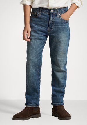 Siniset farkut suoralla lahkeella, viisi taskua ja hienovarainen haalistuminen. Yhdistetty ruskeisiin mokkanahkaisiin nilkkasandaaleihin.