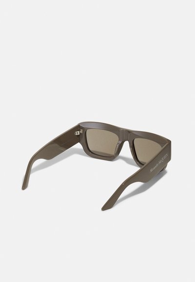 Ochelari de soare din plastic maro, cu un design unghiular, lentile colorate și branding gravat pe brățări. Finisaj texturat și formă îndrăzneață.