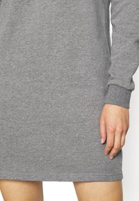 Vestido de sudadera de algodón gris con mangas largas, puños acanalados y corte recto. Textura suave con una superficie lisa y uniforme.
