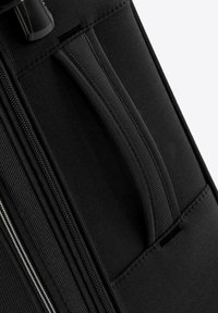 Valise en tissu noir avec une surface texturée, dotée de fermetures éclair, d'une poignée supérieure et de coutures renforcées pour la durabilité.