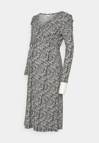 Vestido de maternidade com padrão de zebra em preto e branco, mangas longas, um design envolvente e uma cintura ajustada com detalhes de babados.