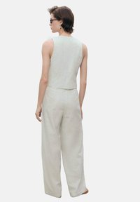 Lys grå linned to-delt sæt, bestående af en ærmeløs cropped top og brede bukser, vist fra ryggen med minimale detaljer.