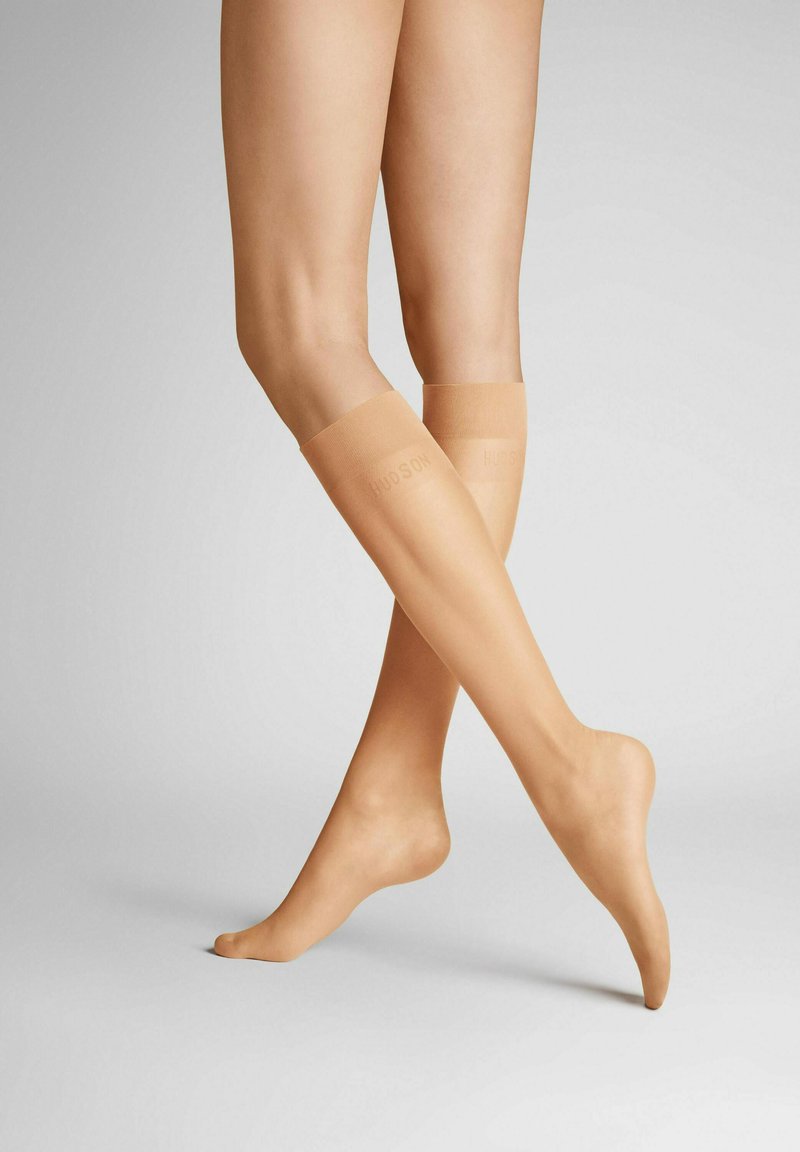 Hautfarbene knielange Socken mit glatter Textur und verstärkten Bündchen, die das "HUDSON"-Logo am Bund zeigen.