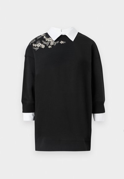 Μαύρο φόρεμα με φούτερ και λευκό γιακά, με διακοσμητική κεντητή ανθοκομία στον αριστερό ώμο. Μακριά μανίκια και ριμπ μανσέτες.