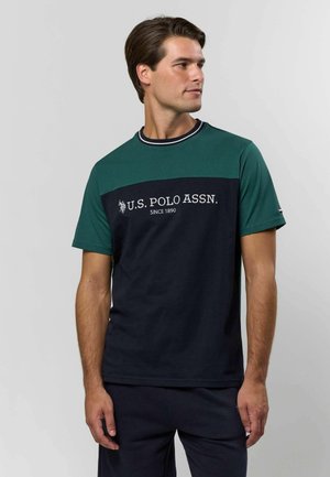 Lühikeste varrukatega T-särk, millel on rohelised ja tumesinised värvilised plokid, puuvillmaterjal, ümmargune kaelus ja valge U.S. Polo Assn. logo.