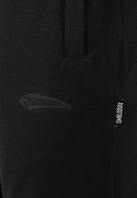 Sorte sweatpants med en glat tekstur, et strømlinet design og en subtil prægning af logoet på låret, samt et lille stofmærke på siden.