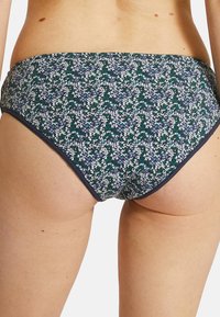 Bas de bikini imprimé floral en bleu marine, présentant de petits motifs bleus et verts, en tissu doux, avec un bord élastique pour un ajustement confortable.