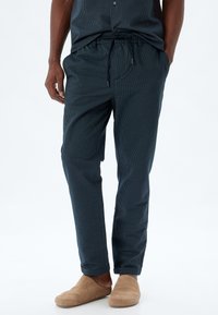 Marinblå randiga byxor i lätt tyg med elastisk midja och dragsnöre, med sidofickor och insvängda ben.