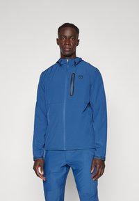 Modrá, lehká bunda se zipovým zapínáním a kapucí. Obsahuje náprsní kapsu se zipem. Hladká textura s dlouhými rukávy, vhodná pro aktivní nošení.