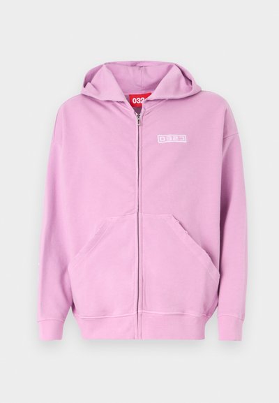 Light pink zip-up hoodie made of soft fabric, featuring a front logo, a spacious kangaroo pocket, and a drawstring hood.