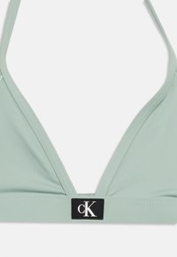 Μπικίνι τοπ σε ανοιχτό πράσινο χρώμα με μαύρο ορθογώνιο λογότυπο CK στο κέντρο της ταινίας κάτω από τις θήκες.