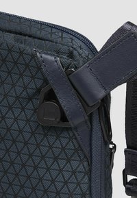 Borsa blu navy con motivo triangolare, caratterizzata da una superficie strutturata, tracolle in pelle e una chiusura sicura per fissare la tracolla.