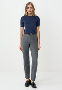 Marineblaues Kurzarmoberteil kombiniert mit grauen, schmal gestreiften, maßgeschneiderten Hosen, die einen slim fit, einen Gürtel und schwarze Slipper aufweisen.