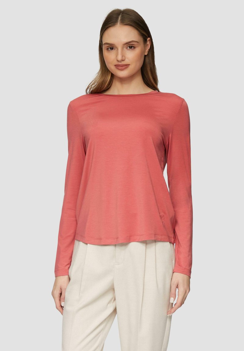 Koraalkleurig shirt met lange mouwen van gladde stof, met een boxy pasvorm, ronde halslijn en zijsplitten, gecombineerd met lichte, loszittende broek.