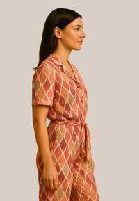 Combinaison à motifs de feuilles rouge et beige avec des manches courtes, un col et une taille ceinturée, fabriquée en tissu léger et texturé.