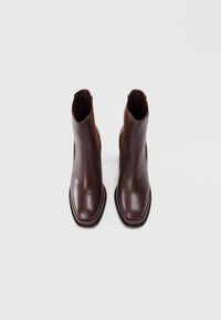 Bottines en cuir marron avec une finition lisse, dotées de panneaux latéraux élastiques et d'un design à bout carré. Semelle plate avec des accents de coutures discrètes.