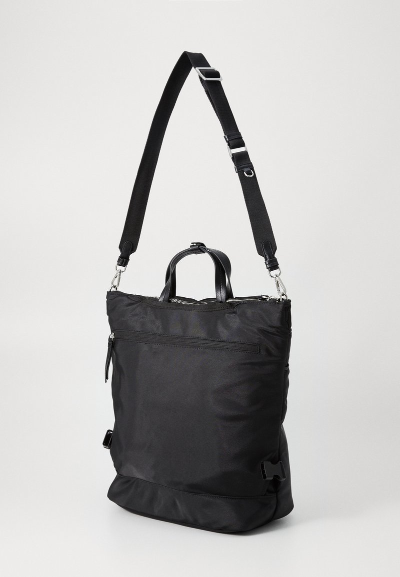 Zaino in nylon nero con tracolla regolabile, maniglia superiore, tasca frontale con zip e dettagli in metallo. Texture liscia, forma rettangolare.