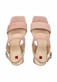 Różowe zamszowe sandały w odcieniu bladego różu charakteryzują się szerokimi paskami i kwadratowym noskiem, mają zapięcie na kostkę z tyłu oraz srebrną klamrę do regulacji.