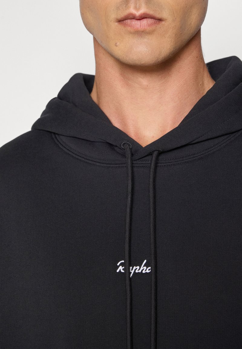 Sort hoodie lavet af glat stof, med en hætte med snøre og hvidt broderet logo på brystet. Teksturen ser blød og tæt ud.