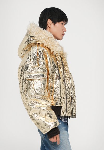Gouden pufferjack met glanzend, reflecterend materiaal, met een bontgevoerd kapsel en ribgebreide manchetten. Textuur oppervlak en details van zijzakken.
