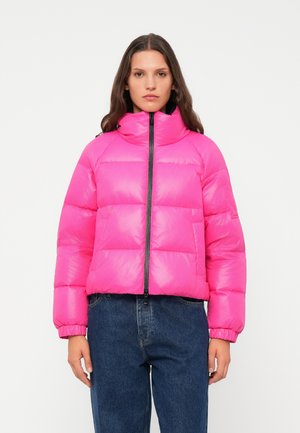 Roze pufferjack met hoge kraag, ritssluiting aan de voorkant en elastische manchetten. Bevat een gewatteerd ontwerp en een oversized pasvorm, gecombineerd met blauwe jeans.