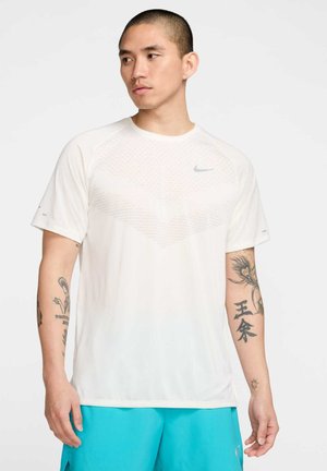 Weißes Kurzarm-Sportshirt mit einem strukturierten Muster auf der Brust, runder Ausschnitt und kleinem grauem Nike-Logo.