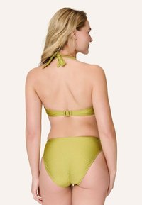 Il set di bikini verde oliva presenta un top a fascia con chiusura a legaccio e slip a vita alta abbinati. Texture liscia e lucida. Vestibilità regolabile.
