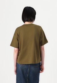 Olivgrünes Baumwoll-T-Shirt mit kurzen Ärmeln, lässigem Schnitt und Rundhalsausschnitt, von hinten betrachtet. Weicher Stoff, schlichtes Design.