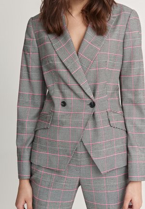 Šedé dvouřadé kárované sako s růžovými linkami, nošené s odpovídajícími károvanými kalhotami, zobrazeno od krku po boky.