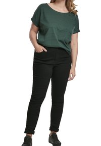 Pruhovaný zelený krátký rukávový top, volný střih, kombinovaný s přiléhavými černými džíny a černými teniskami. Casual outfit s ohrnutými manžetami.