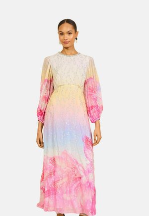 Kvinde iført en lang, pastel ombré kjole med lyserøde blomsterprint og sølvpynt, med puffede lange ærmer og en tætsiddende talje.