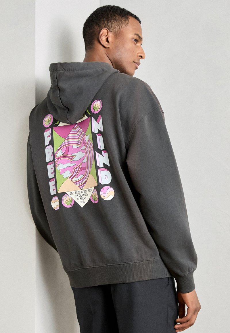 Grijze hoodie met een groot, kleurrijk grafisch ontwerp op de achterkant met de tekst "FREE MINDS" en abstracte patronen, gemaakt van een zachte stof.