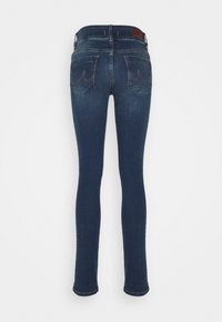 Jeans ajustados de mezclilla azul oscuro, con una cintura de altura media, dos bolsillos traseros y un dobladillo limpio con un detalle mínimo.