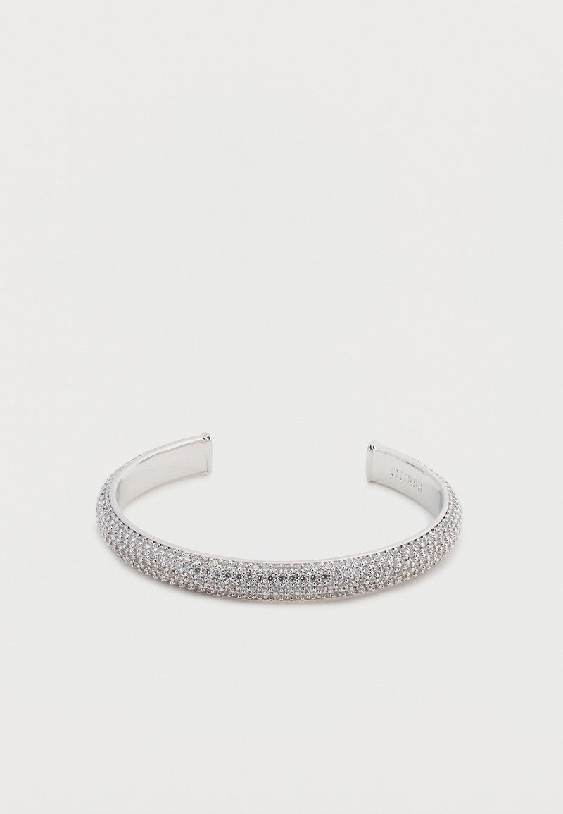 Bracelet manchette en argent avec une surface lisse et polie et une rangée de petites pierres claires le long du bord supérieur. Matériau en métal durable.