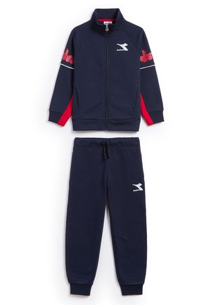 Tuta da ginnastica blu navy con giacca con zip e pantaloni con vita elastica. Presenta dettagli rossi e un logo, realizzata in un morbido tessuto testurizzato.