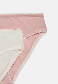 Two cotton women's underwear, one light pink and one cream, with scalloped lace trim on white background.