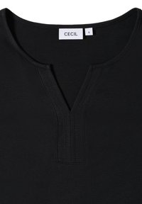 Schwarzes Baumwollshirt mit rundem Ausschnitt und kurzem V-Ausschnitt, mit einem sichtbaren weißen Etikett, das "CECIL" und die Größe "S" trägt.