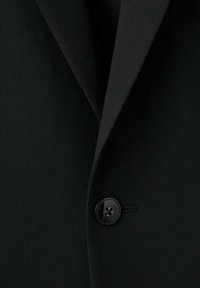 Zwart colbert met focus op een enkele zwarte knoop, revers en gladde stoftextuur.