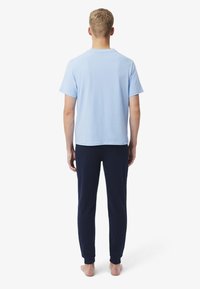 T-shirt bleu clair à manches courtes et col rond, associée à un pantalon de survêtement bleu marine avec poignets élastiques.