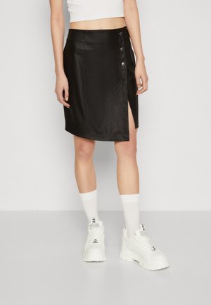 Jupe en simili cuir noir avec une fente latérale, dotée de détails avec boutons-pression. Texture lisse, design ajusté et longueur mi-cuisse.